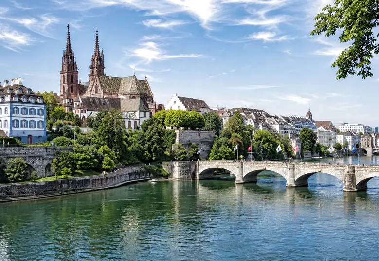 Basler Münster mit den roten Türmen über dem Rhein und der Mittleren Brücke – ReparFix vermittelt Oberflächenreparaturen an Partnerbetriebe in Basel, die vor Ort reparieren.